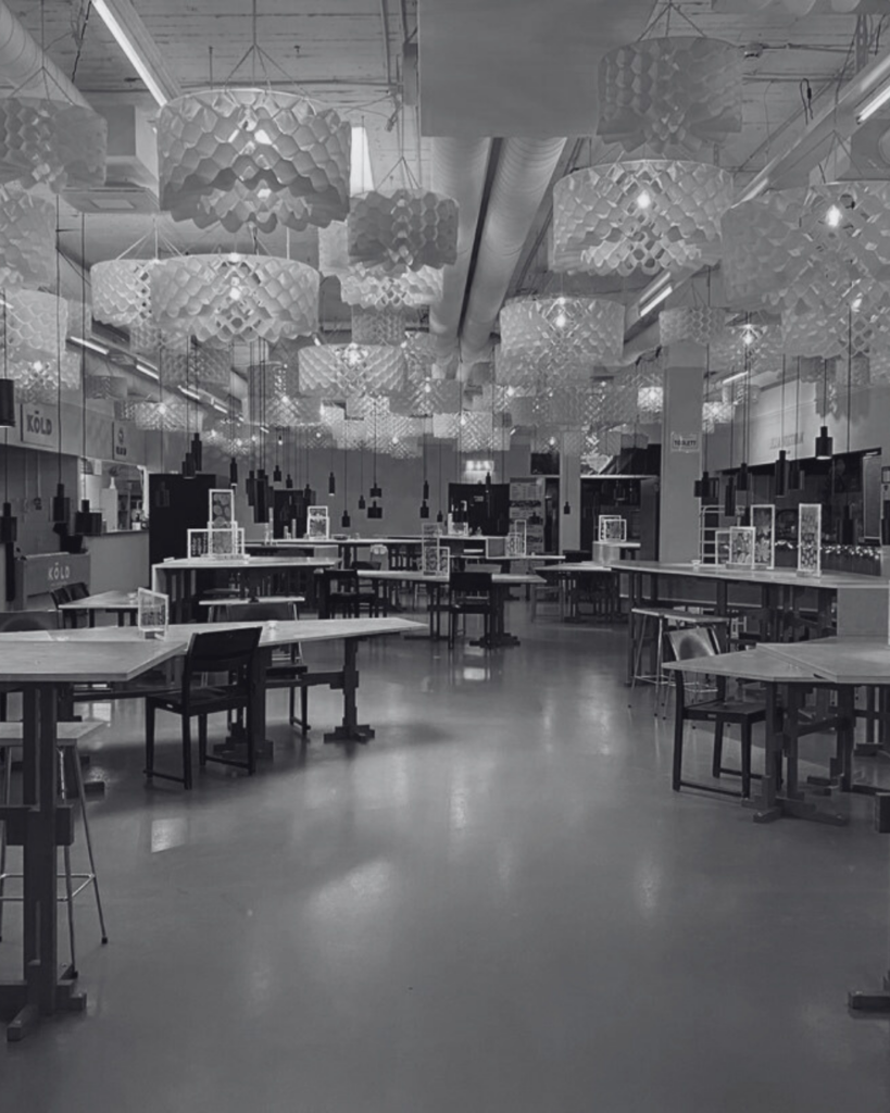 Vy över en modern foodcourt med öppna ytor, matstånd och dekorativa taklampor i tyg.